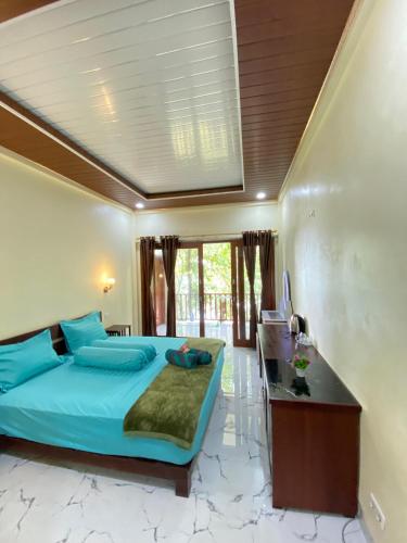 a bedroom with a blue bed and a desk at Pele's Place Coral Reef Bungalows & Café Maman in Sabang