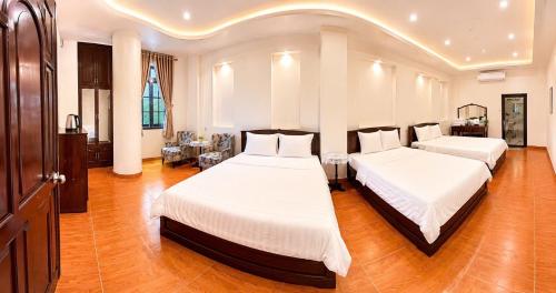 two beds in a large room with wood floors at Khách Sạn Mỹ Kim in Cà Mau