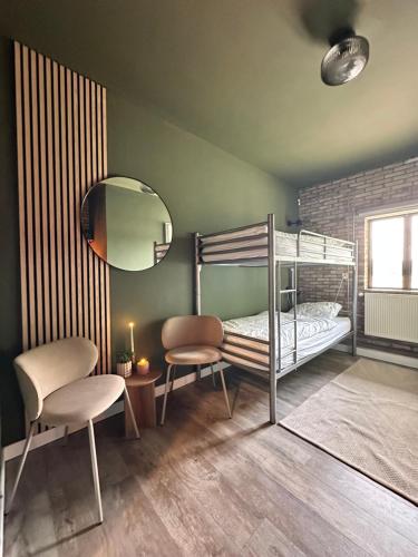 a bedroom with a bunk bed with a mirror and chairs at B&B Landgoed de Bossenhoeve in Schayk