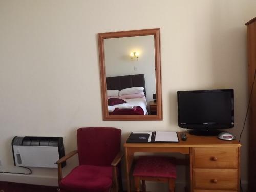 a room with a desk with a tv and a mirror at Palace Hotel - Small Hotel in Oban