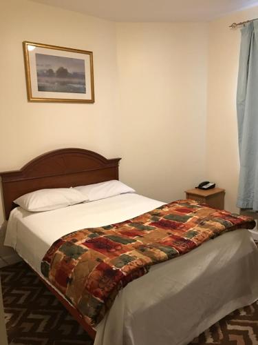 a bedroom with a bed with a quilt on it at Waterbury Big Apple Motel in Waterbury