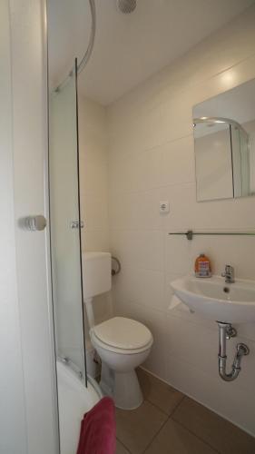 a white bathroom with a toilet and a sink at Berl Inn in Berlin