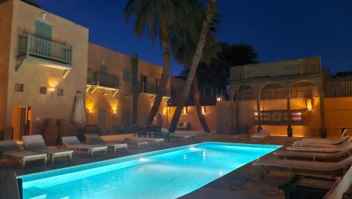 a swimming pool with lounge chairs and a building at Habu Hotel in Al Aqālitah