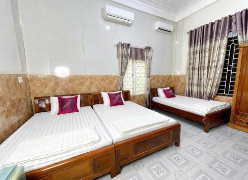 a bedroom with two beds and two windows at Long Khang Hotel in Quang Tri
