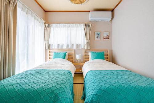 two twin beds in a room with a window at MARSEA Resort in Zushi