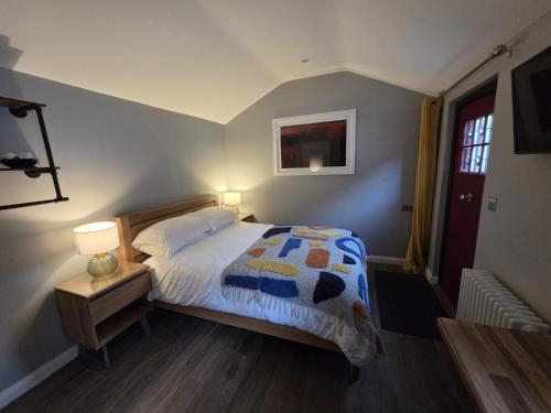 a bedroom with a bed and a table with a lamp at Garden Lodge in Belfast