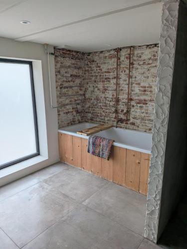 a bath tub in a room with a brick wall at BoerLangendijk in Rucphen