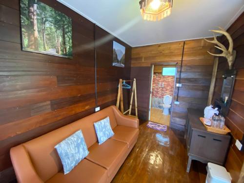 a living room with a couch and wooden walls at มาดูดอย - Madoodoi in Ban Mae Na