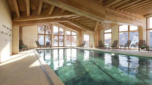 a large swimming pool with chairs and windows at Résidence Pierre & Vacances Capella in Avoriaz