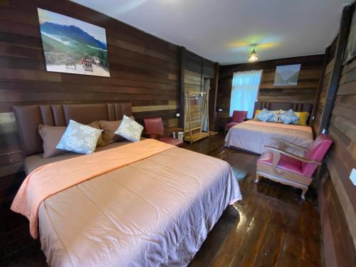a hotel room with two beds and a chair at มาดูดอย - Madoodoi in Ban Mae Na