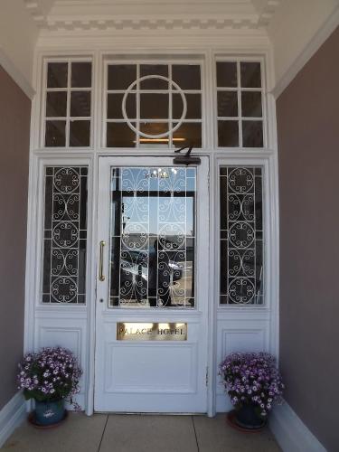 a white door with windows and two vases with purple flowers at Palace Hotel - Small Hotel in Oban
