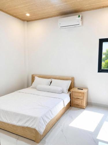 a white bedroom with a bed and a window at Phước Hải Đẹp Homestay in Chợ Phước Hải