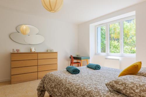 a bedroom with a bed and a dresser and windows at Charmante Maison Vallon pont d'Arc in Vallon-Pont-dʼArc