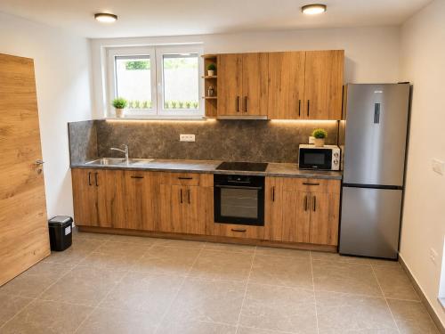 a kitchen with wooden cabinets and a stainless steel refrigerator at Apartment Beli in Radovljica