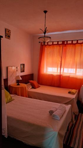 a bedroom with two beds and a window with orange curtains at Casa do Vicente in Tabuaço