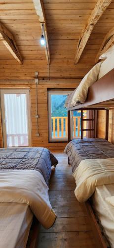 two beds in a wooden room with a window at Livadhi Guesthouse in Mollʼ e Shoshit