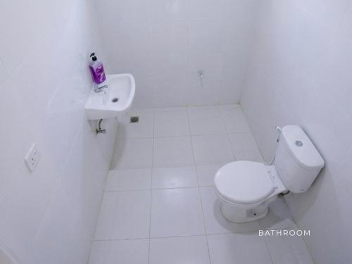 a white bathroom with a toilet and a sink at The Clifftop Home in Esperanza
