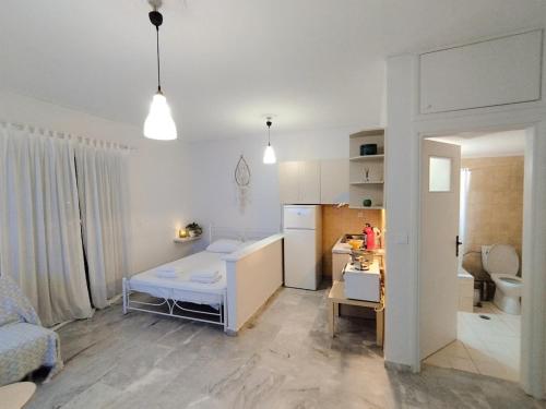 a small white room with a bed and a kitchen at Cucuvaya Rithy in Áyios Andónios