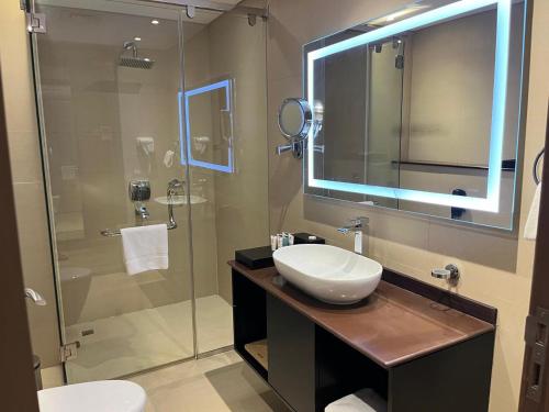 a bathroom with a sink and a glass shower at Carnelian Muscat - Airport Hotel in Muscat