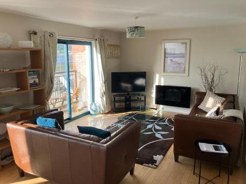 a living room with two couches and a television at John's Luxury Seafront Apartment in Newcastle