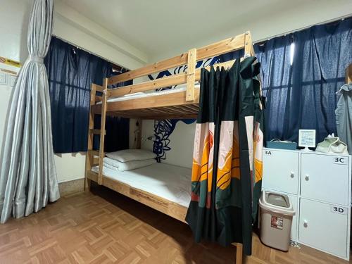 a bedroom with bunk beds in a room with blue curtains at HouseNandoor in Tainan