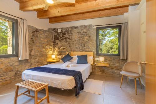 a bedroom with a bed and a stone wall at Mas Ca la Rossa in Girona