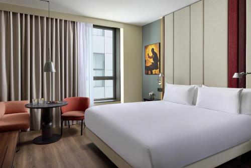 a hotel room with a large white bed and a table at NH Barcelona Diagonal Poblenou in Barcelona