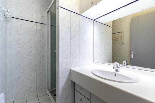 a white bathroom with a sink and a shower at La Canopée - Conciergerieland in Soustons