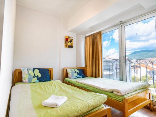 two beds in a room with a large window at Villa Apollo Ohrid Lakeside in Ohrid
