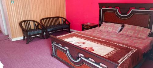a bedroom with a large bed and two chairs at Stone Man's Hotel Samana Heights in Battakundi