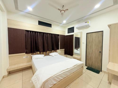 a bedroom with a large white bed and a window at Shri Gopal Durga Dham Hotel And Restaurant in Ujjain
