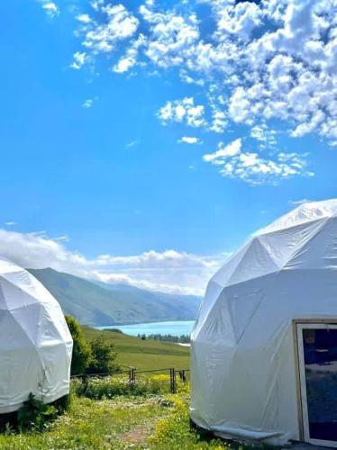 two white tents in a field with a view of a mountain at Lakeside glamping in Tsovagyugh