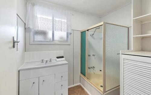 a white bathroom with a shower and a sink at Beach Side on Burke - Pet Friendly in Golden Beach