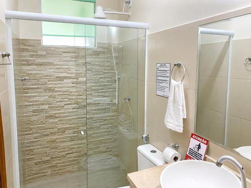 a bathroom with a glass shower with a toilet at Hosts BR - La Serena Suíte Cumbuco in Caucaia