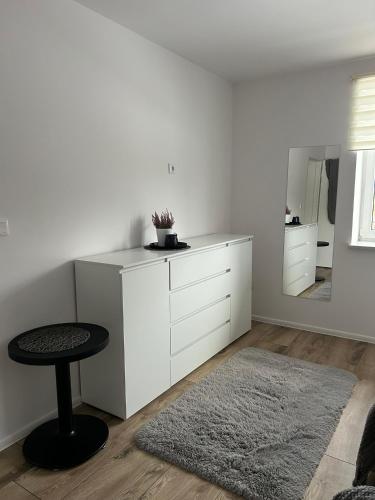 a white living room with a stool and a mirror at Noclegi Leśne Bagno in Zwierzyniec