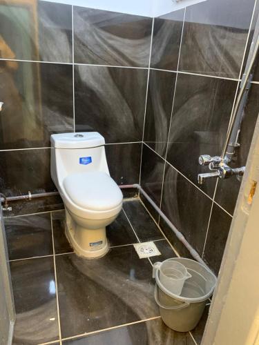 a bathroom with a toilet in a black tiled wall at Nour Taba Apartments in Medina
