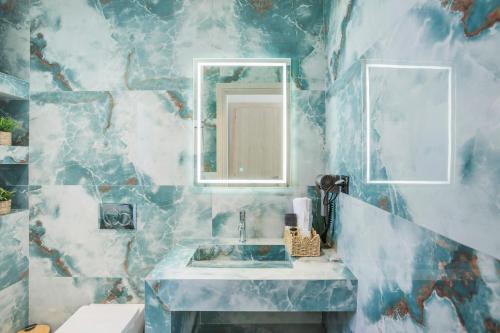 a blue marble bathroom with a sink and a mirror at Adessa Villas in Afitos