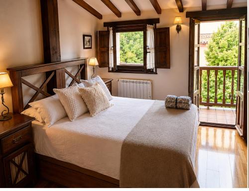 a bedroom with a large bed and two windows at La Senda del Norte in Cabezón de la Sal