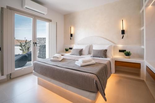 a bedroom with a large bed and a large window at Serenity Collection Suites in Karterados