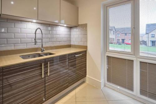 a kitchen with a sink and a window at House Sleeps 8 with WiFi in Corby
