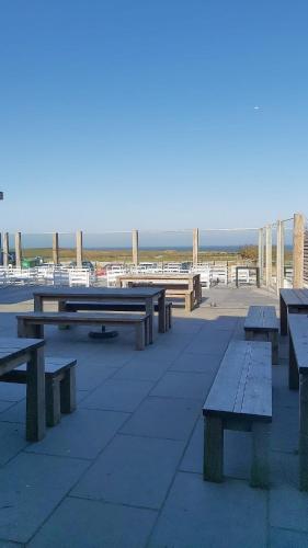 a group of picnic tables in front of the beach at The Dormy House Hotel in Cromer