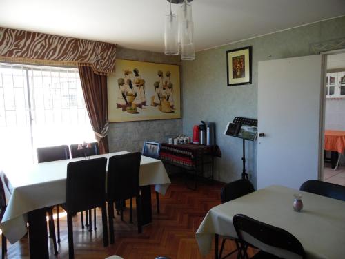 a dining room with tables and chairs and a television at Hostal Tunquelen in Valparaíso