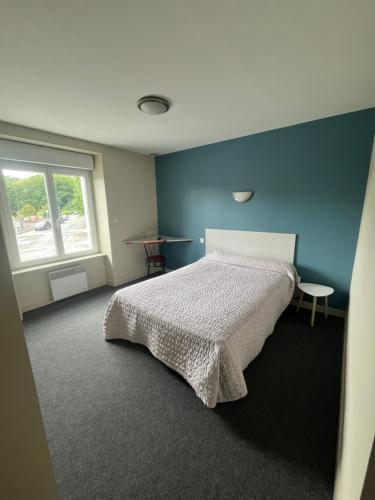 a bedroom with a bed and a blue wall at Hôtel des Voyageurs in Changé