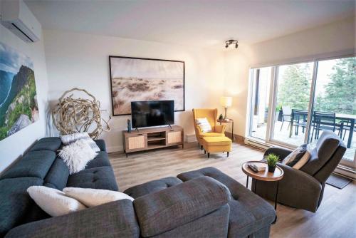 a living room with a couch and a tv at Terrace Condo with River View and Pool in Baie-Saint-Paul