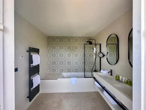 a bathroom with a tub and a sink and mirrors at Château de Pizay in Belleville-sur-Saône