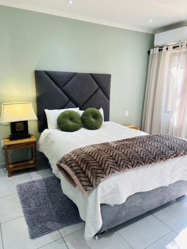 a bedroom with a large bed with two green pillows at Little Haven Conerstone cottage in Windhoek