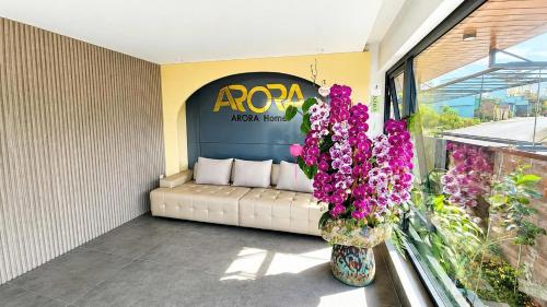 a couch in a room with flowers in a window at Arora Home Pleiku in Pleiku