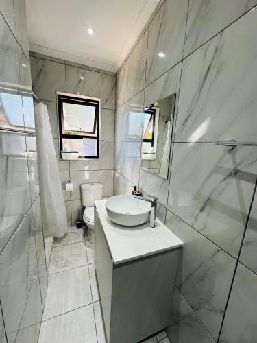 a bathroom with a sink and a toilet and a mirror at Little Haven Conerstone cottage in Windhoek