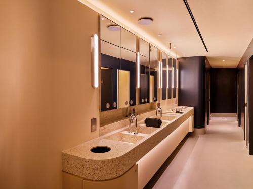 a bathroom with three sinks and a row of mirrors at Otherwander Soho Pod Hotel in London
