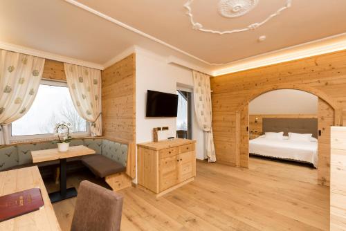 a large room with a bed and a desk and a television at Sporthotel Arabba in Arabba